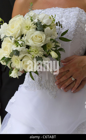 American young couple bride with groom hands with the wedding rings and bouquet of white roses very high resolution in USA US vertical format hi-res Stock Photo