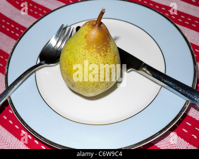 Pear on a plate with knife and fork Stock Photo