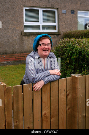 Susan Boyle in high spirits while happily chatting to photographers outside her house, wearing a blue hat and striped shirt. Stock Photo