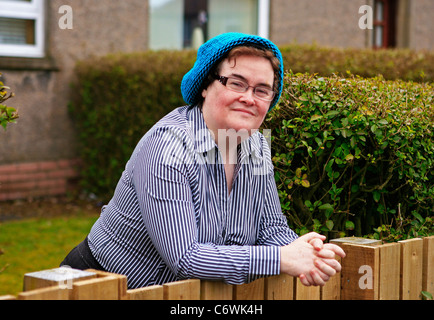 Susan Boyle in high spirits while happily chatting to photographers outside her house, wearing a blue hat and striped shirt. Stock Photo