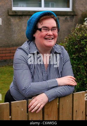 Susan Boyle in high spirits while happily chatting to photographers outside her house, wearing a blue hat and striped shirt. Stock Photo