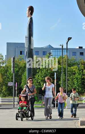 Family with children walking past sculpture The Long Banker / Langer Baenker at the Kirchberg plateau, Luxembourg Stock Photo