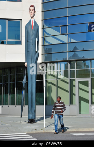 Black man and sculpture The Long Banker / Langer Baenker in front of the Deka Bank at the Kirchberg plateau, Luxembourg Stock Photo