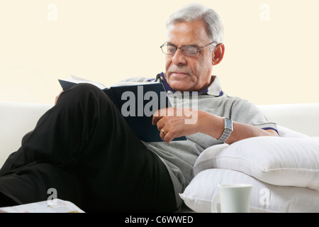 Old man reading a book on a sofa Stock Photo