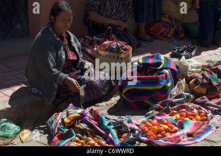 A woman selling tomatoes in Chichicastenango street market, Guatemala, has her goods wrapped in the most gorgeous woven fabrics. Stock Photo