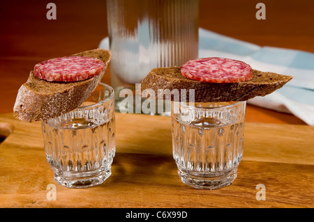 Two little glasses of vodka and sandwich with rye bread and sausage. Stock Photo