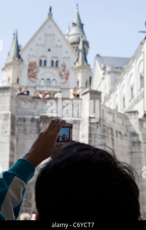 Tourist taking pictures of Neuschwanstein castle with digital camera. Bavaria Germany Stock Photo