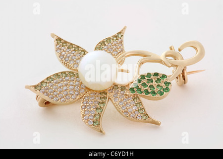 Golden brooch in the form of a flower with a pearl and stones on white background Stock Photo
