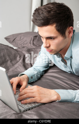Man using laptop on bed Stock Photo