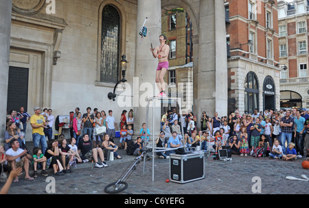 Busker male performer juggling with a chain saw in Covent Garden London UK Stock Photo