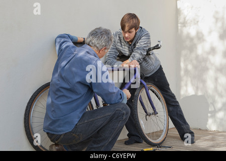 Father helping son repair bicycle Stock Photo