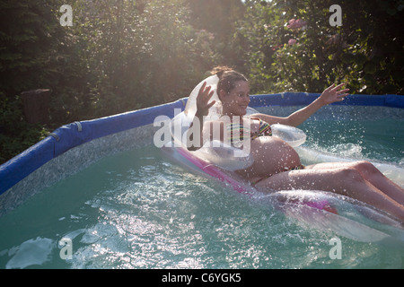 Pregnant woman floating in pool Stock Photo