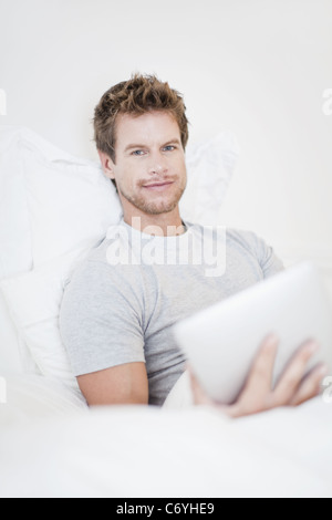 Man using laptop in bed Stock Photo