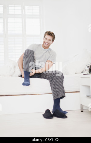 Man putting socks on in bed