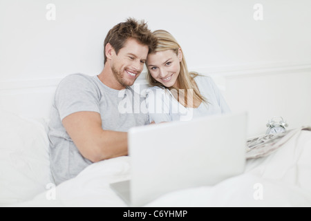 Smiling couple using laptop in bed Stock Photo