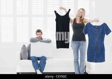 Woman picking out clothes in living room Stock Photo