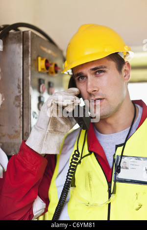 Worker talking on phone on oil rig Stock Photo