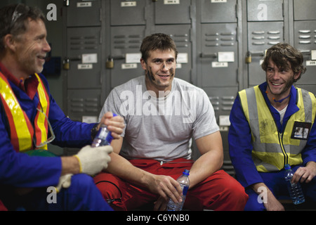 Workers sitting in locker room Stock Photo