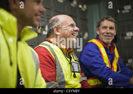 Workers sitting in locker room Stock Photo