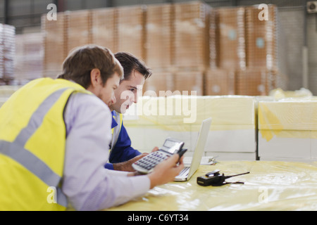 Workers using laptop in warehouse Stock Photo