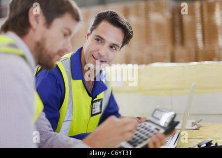 Workers using laptop in warehouse Stock Photo