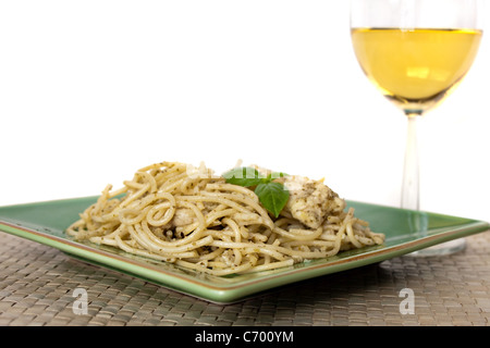 A dish of spaghetti with pesto garlic and chicken with a glass of white wine. Shallow depth of field. Stock Photo