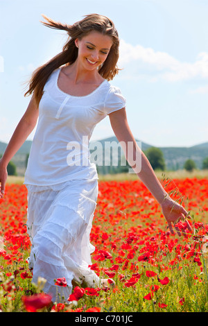 Woman walking in field of poppies Stock Photo