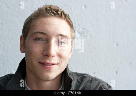 Close up portrait of a handsome smiling young man in his early twenties with dirty blonde hair. Stock Photo