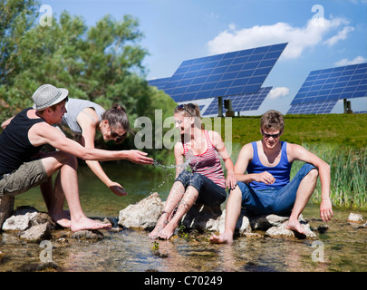 People sitting in river by solar panels Stock Photo