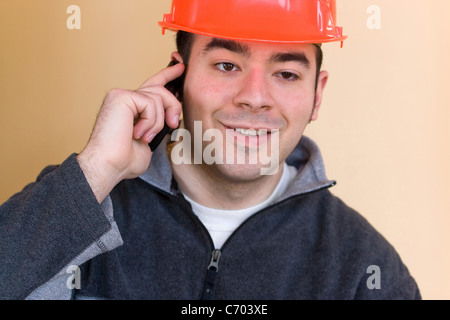 A young construction professional talks on his smartphone. Stock Photo