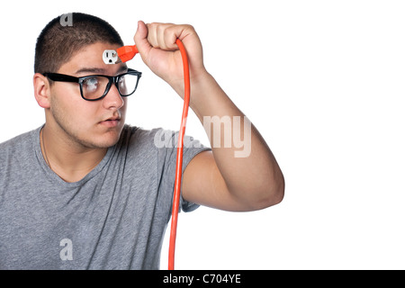 Conceptual image of a young man holding an electrical chord disconnected from the outlet on his forehead. Stock Photo