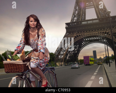 Woman riding bicycle under Eiffel Tower Stock Photo