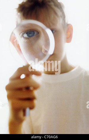 Boy peering through magnifying glass Stock Photo