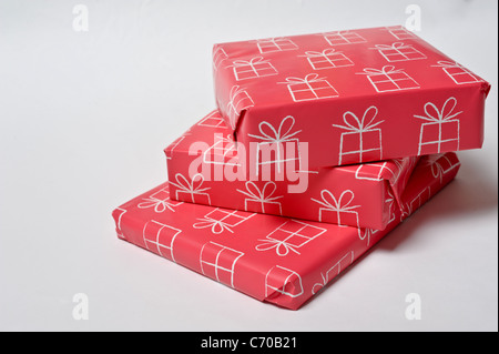 Three birthday presents wrapped up in pink paper and piled up on each other against a plain white background Stock Photo