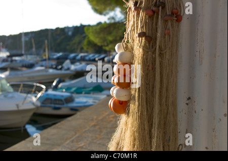 Fishing nets hung up for drying in, lit by the setting sun, Duino harbor, Italy Stock Photo