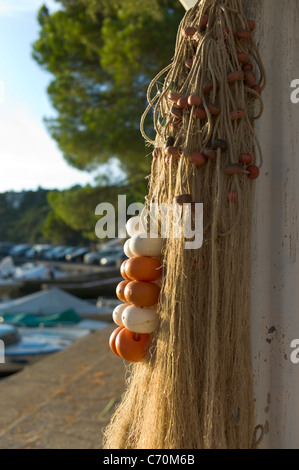 Fishing nets hung up for drying in, lit by the setting sun, Duino harbor, Italy Stock Photo