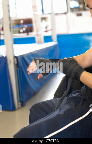 Boxer wrapping his hands in gym Stock Photo