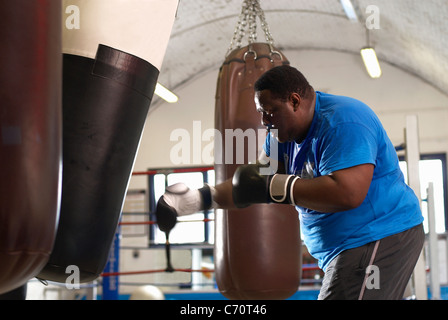 Boxer using punching bag in gym Stock Photo