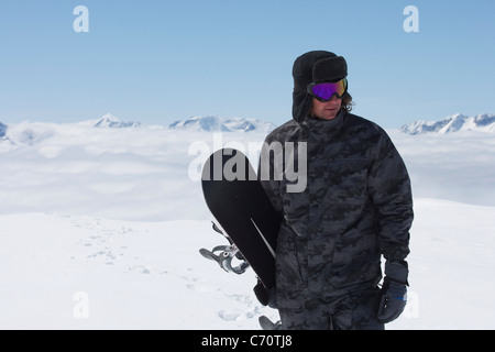 Snowboarder carrying board on slope Stock Photo
