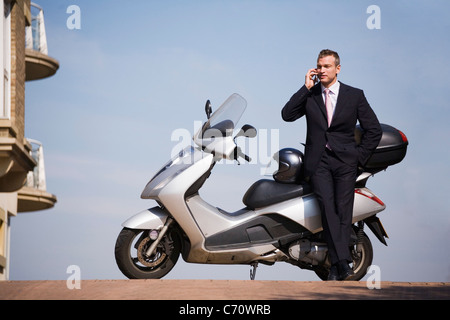 Businessman on cell phone with scooter Stock Photo