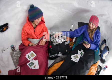 Boy and girl playing cards in snow cave, Silverton, Colorado. Stock Photo