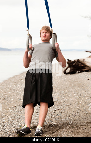 A man uses suspension rings on a beach. Stock Photo