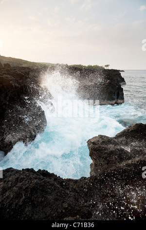 Waves crash over cliffs of lava rock. Stock Photo