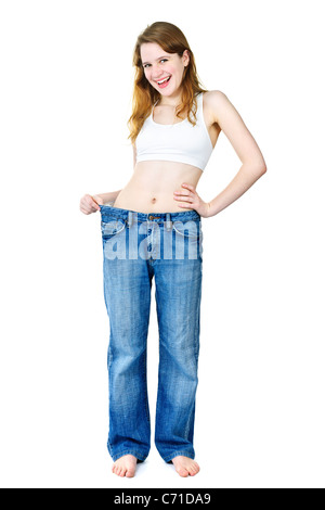 Happy fit young woman in loose old jeans after losing weight isolated on white Stock Photo