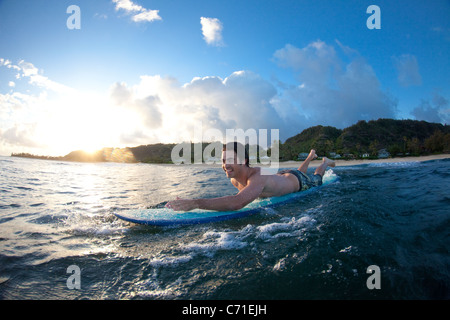 A young man paddling out for a surf at  Monster Mush, on the north shore of Oahu, Hawaii Stock Photo