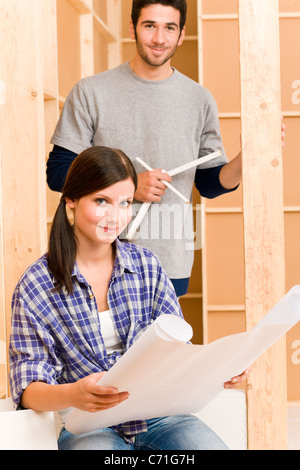 Home improvement happy young couple with architectural blueprints fixing house Stock Photo