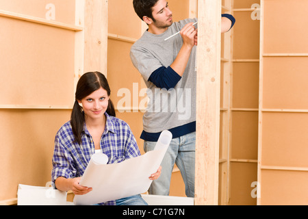Home improvement happy young couple with architectural blueprints fixing house Stock Photo