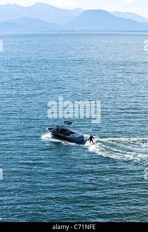 A happy athletic woman wake surfs behind a wakeboard boat in Idaho. Stock Photo