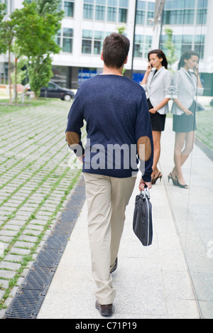 Man walking with briefcase, woman talking on cell phone in background Stock Photo