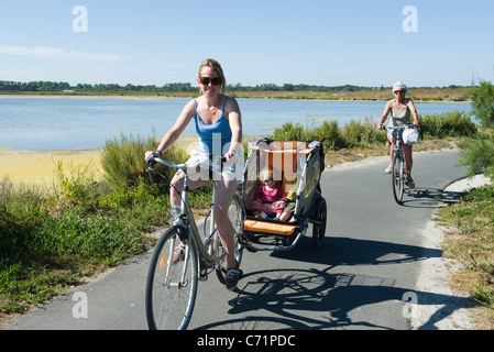 Multi-generation family enjoying bicycle ride, children sitting in bicycle trailer Stock Photo